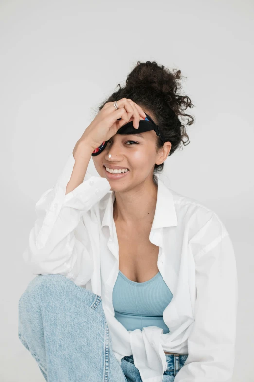 a young woman sitting in the corner wearing a white shirt and jeans