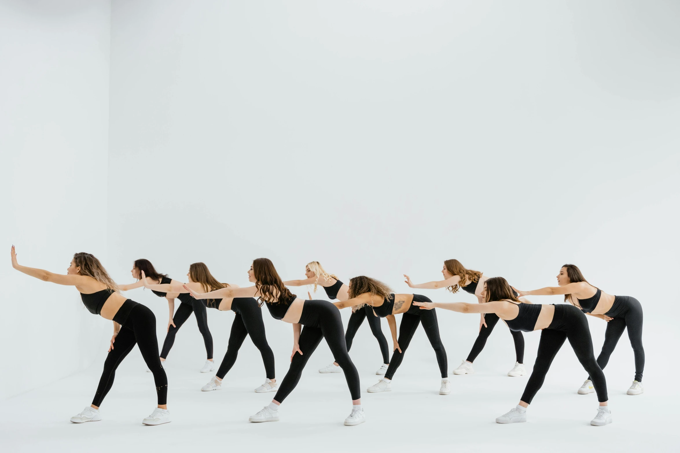 a line of women doing exercises in black tight pants