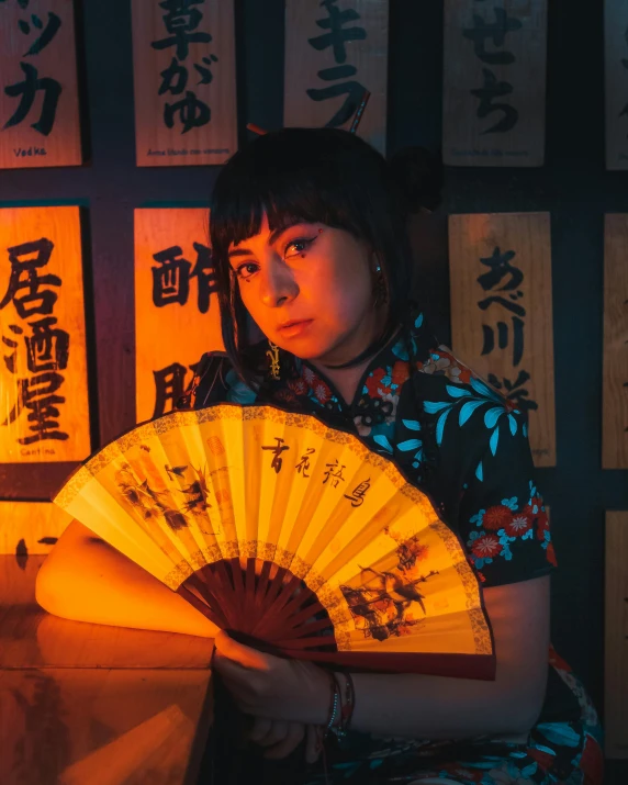 a woman sitting in front of a large japanese fan