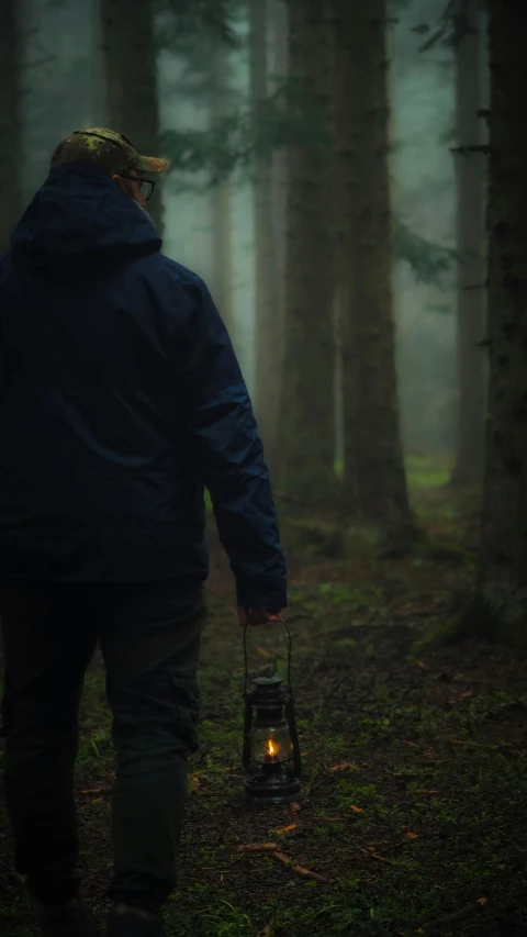 the man with the light in his hand walks through the woods