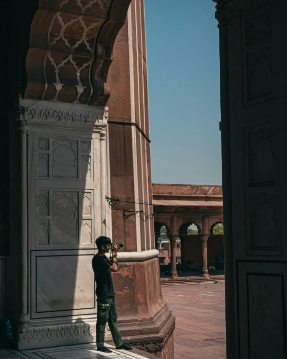 a man is standing under a pillar in a courtyard