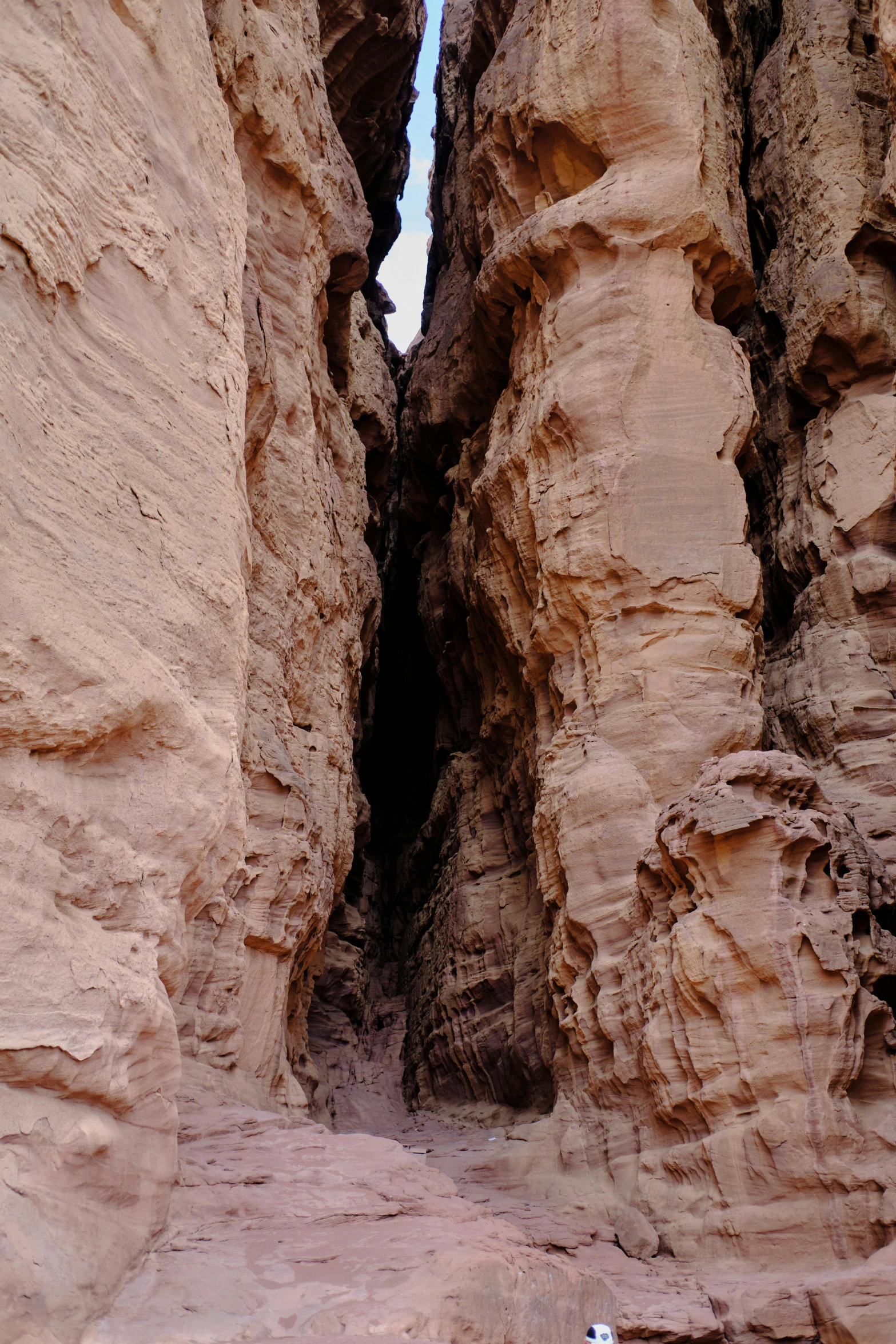 a person is standing in the narrow passage between two rock formations