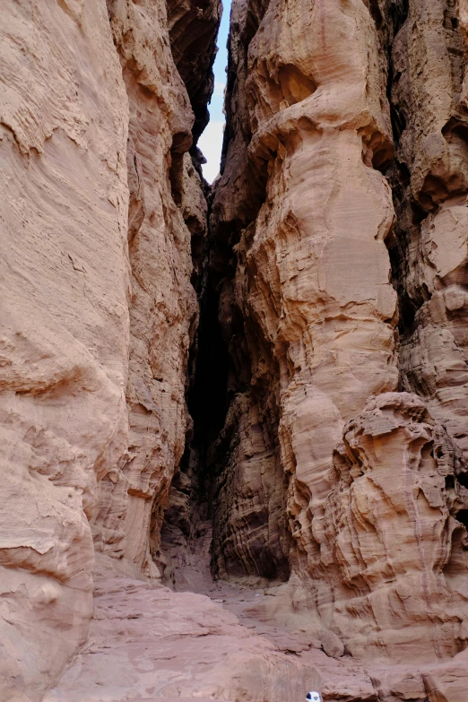a person is standing in the narrow passage between two rock formations