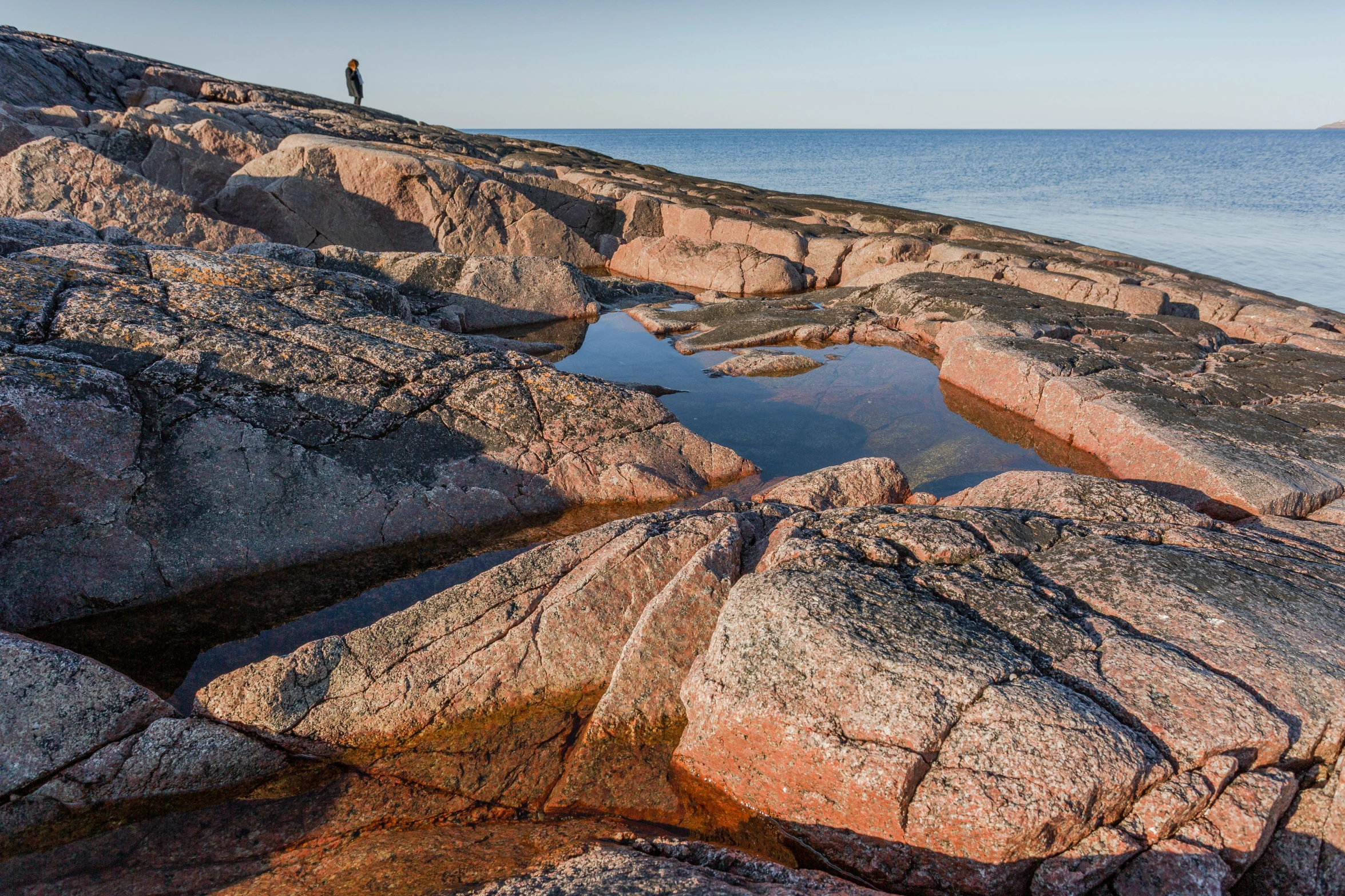 someone standing on the rocky shoreline of a beach