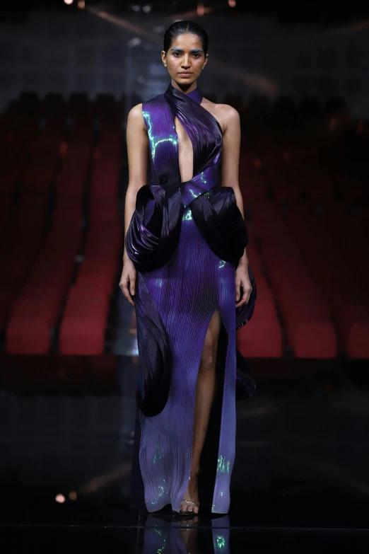 a woman in a purple dress and large purple ballons on the runway
