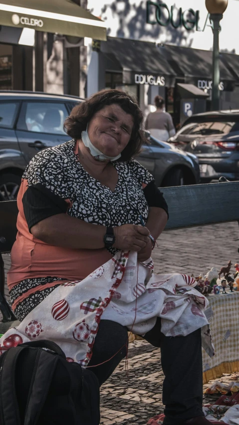 a lady sitting on a street curb holding some material