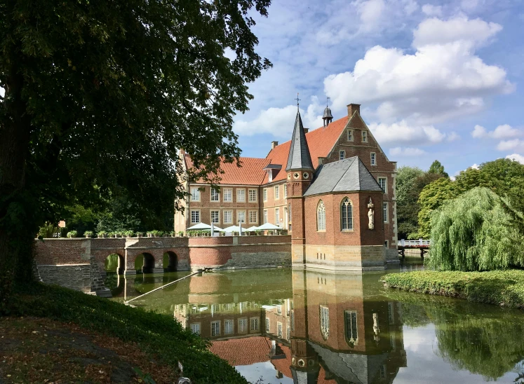 the castle is reflected in the water near the trees