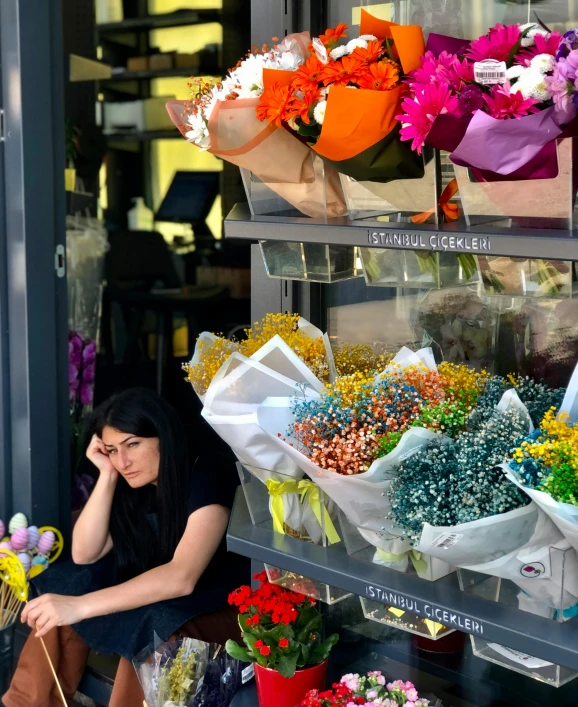 a woman sitting next to a flower shop