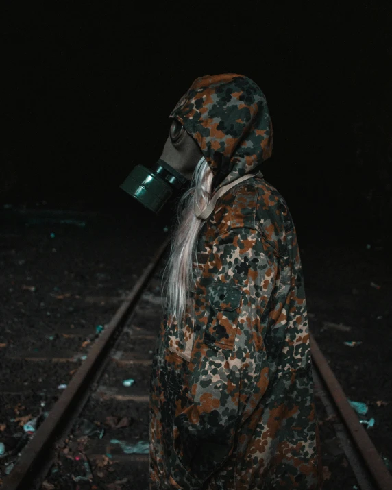 a man in camouflage is walking on railroad tracks