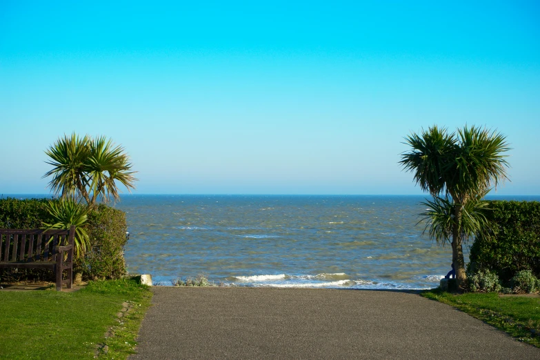 a gravel driveway with a small gate to the beach