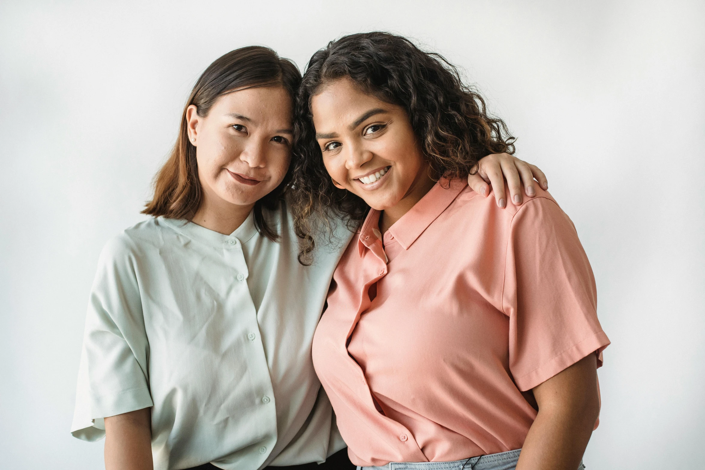 two women posing for the camera in front of a white background