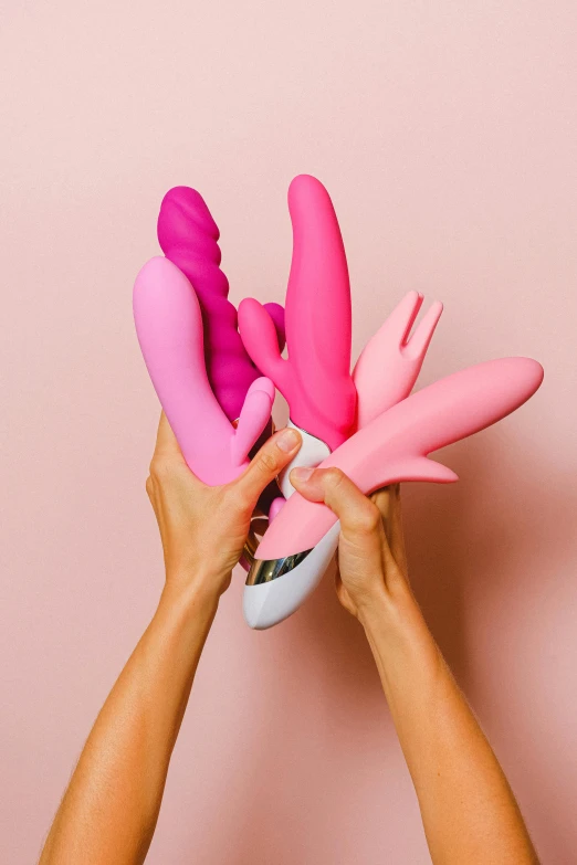 hands holding up pink fake flowers against a pink wall