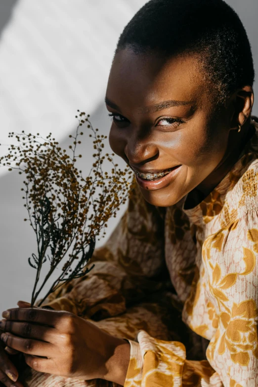 a woman smiles while holding some dried plants