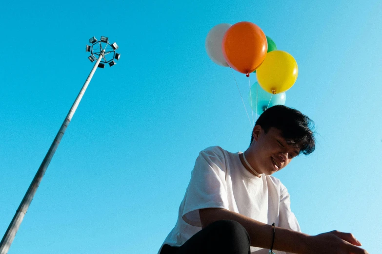 the man is sitting on a post with balloons on it