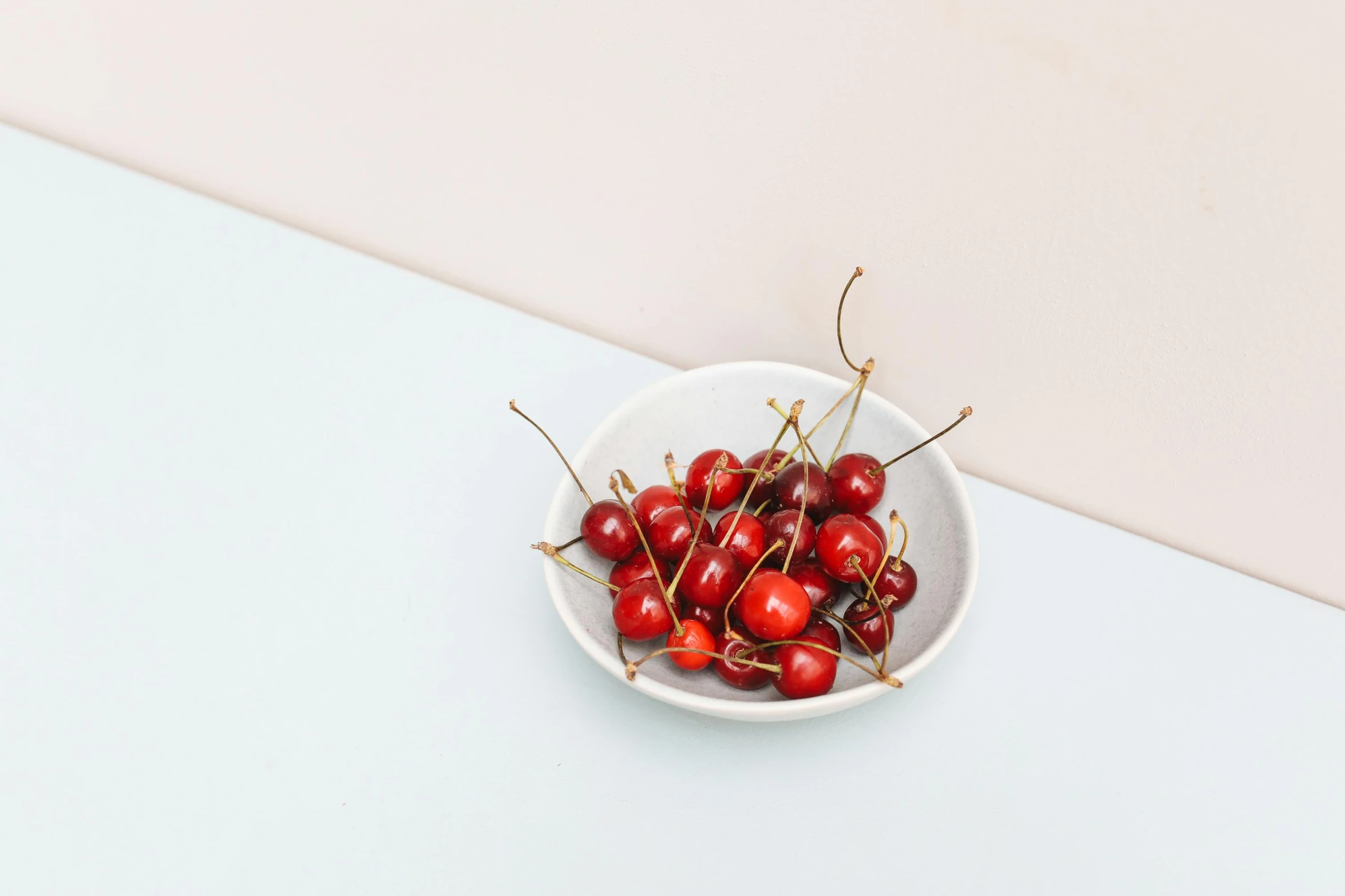 small white bowl with a cluster of cherries in it