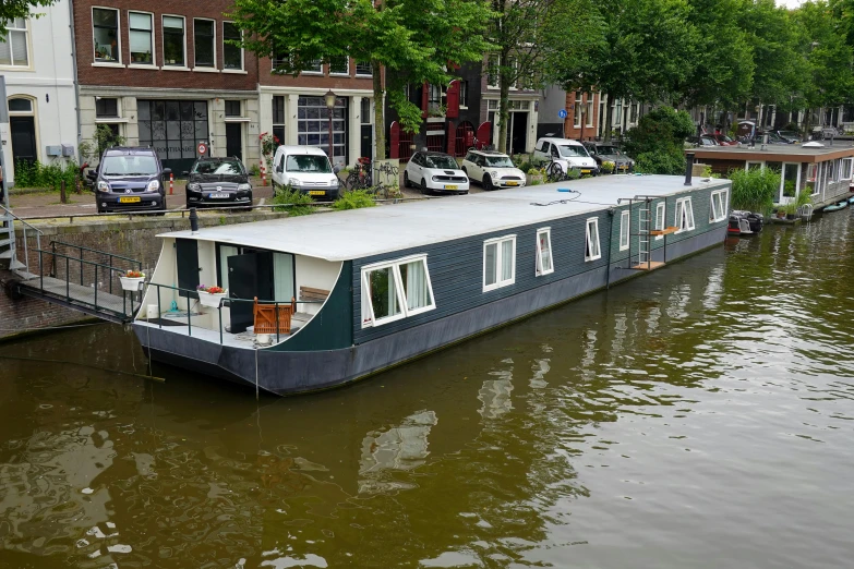 a large houseboat traveling down a river next to tall buildings