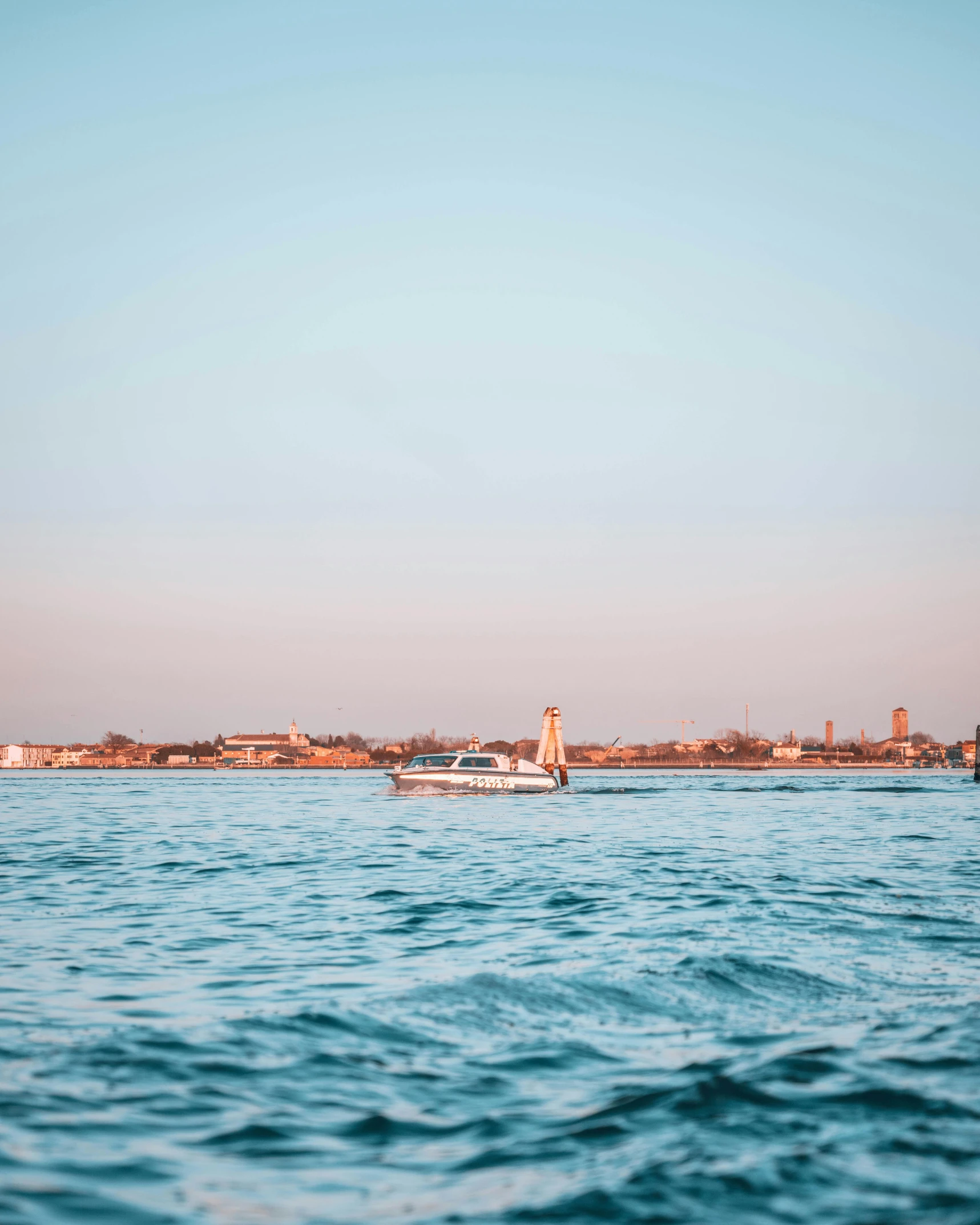 a boat floating on top of the ocean next to tall buildings