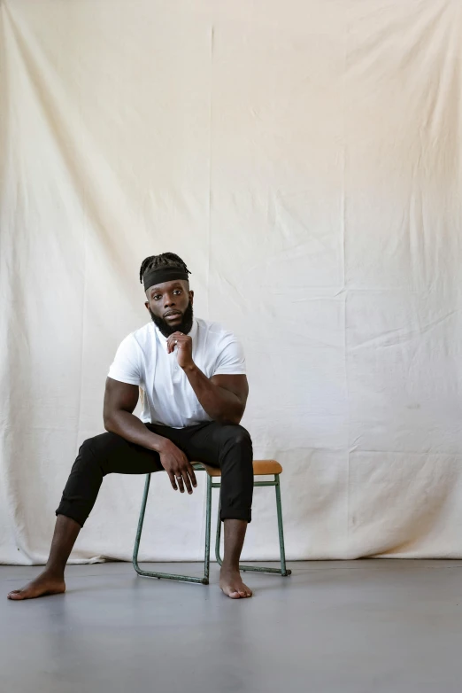 a man sits on a chair in a studio setting