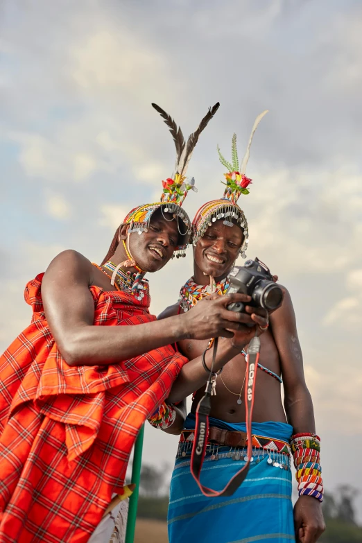 two people in native attire standing and taking pictures