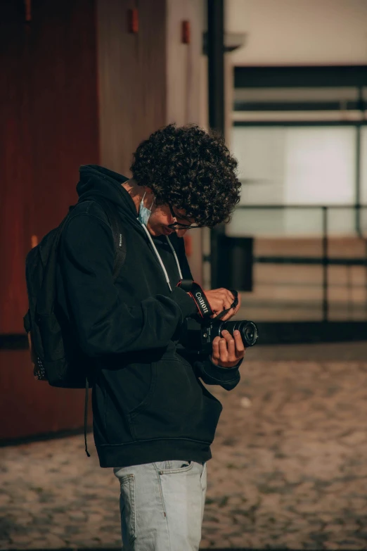 a person holding a camera and looking at his phone