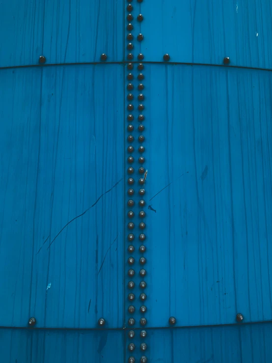 some metal rivets and nail holes on a blue surface