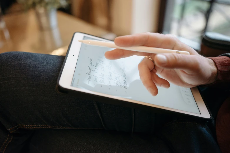 the person is holding a tablet and using a pen