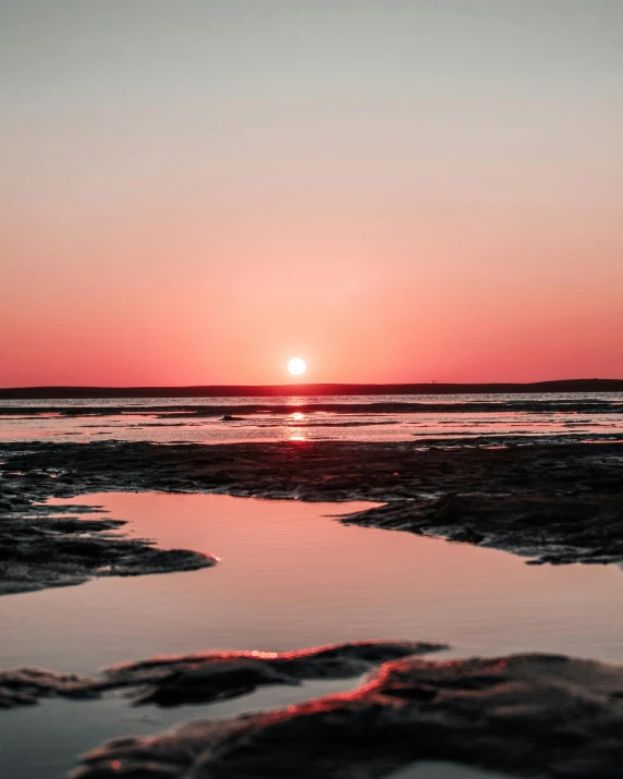 the sun rises over the ocean as the tide breaks into land