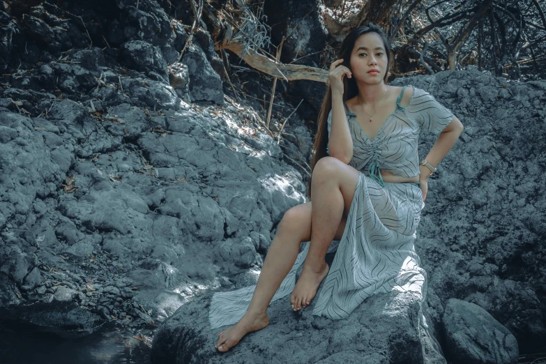 a woman is sitting on a rock outside