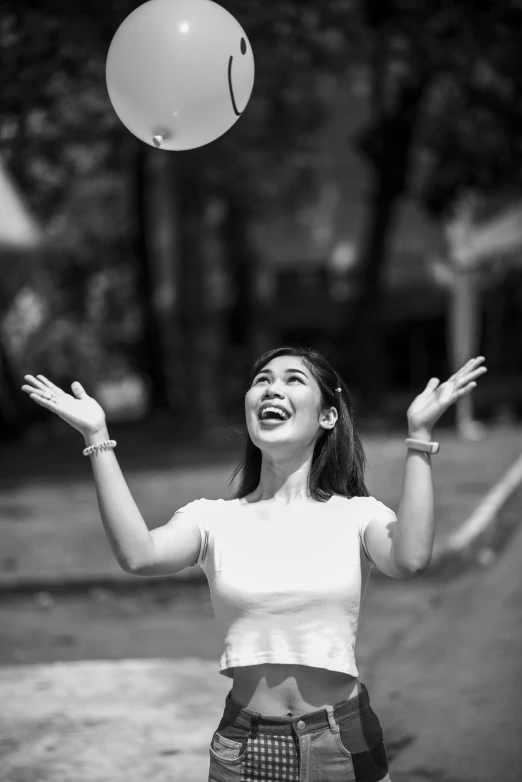 a young woman in shorts and a white shirt is juggling with a smile on her face