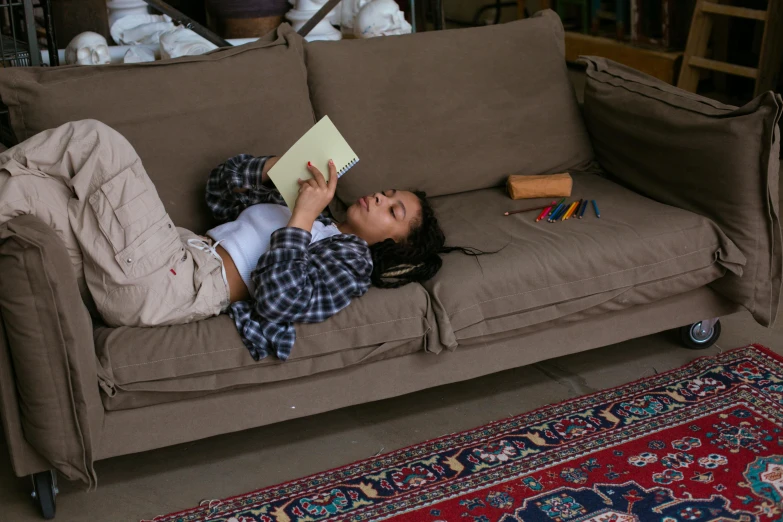 a  laying on the couch reading a book