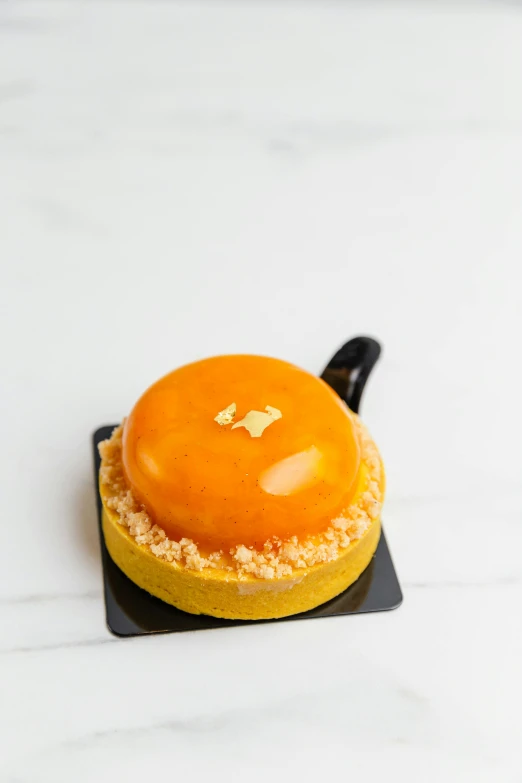 a round orange pastry on a black plate