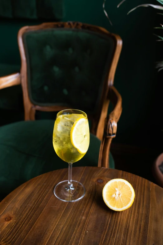 a glass with liquid and a half of lemon sits on a table