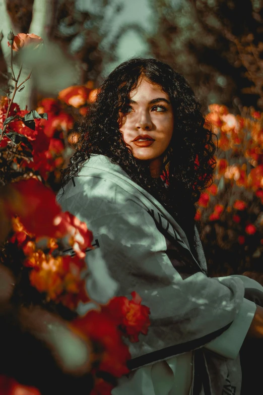 a woman that is standing in front of some flowers