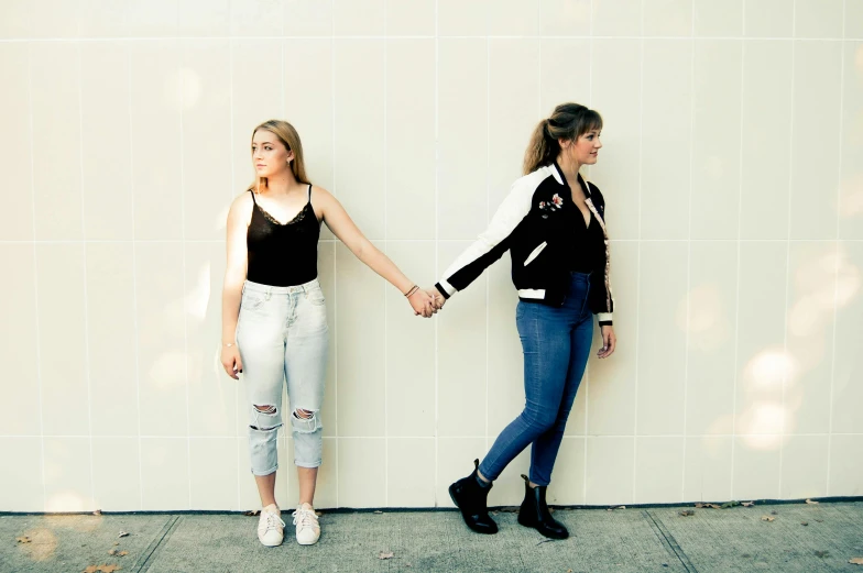 two girls standing next to each other holding hands