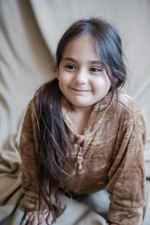 a little girl smiles in her brown sweater