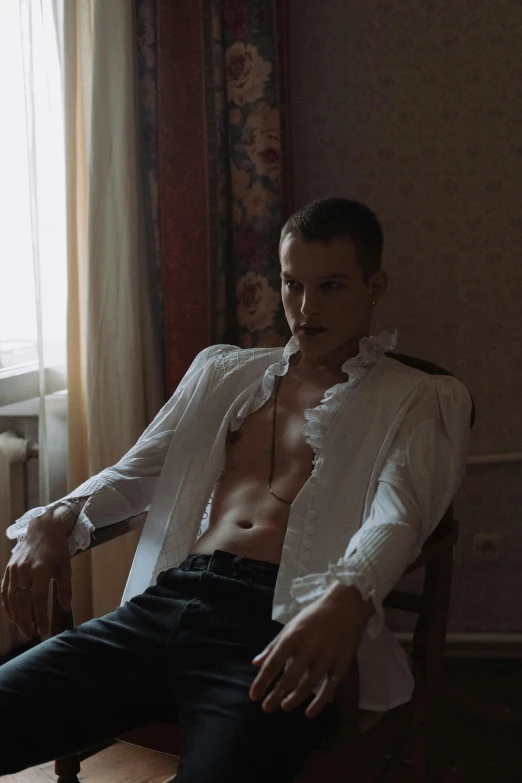 a shirtless man sitting in a chair with his shirt undone