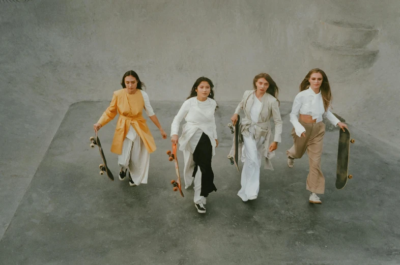 four women walking with skate boards in a parking lot