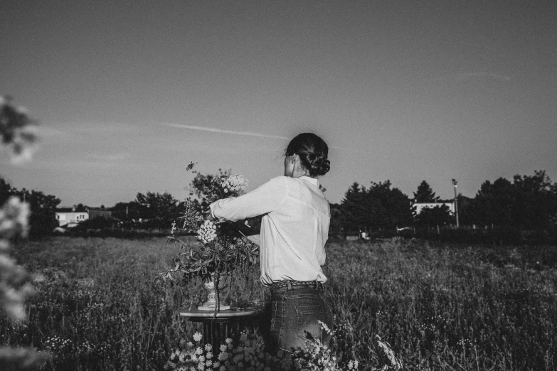 a man is standing in an open field spraying flowers with a hose