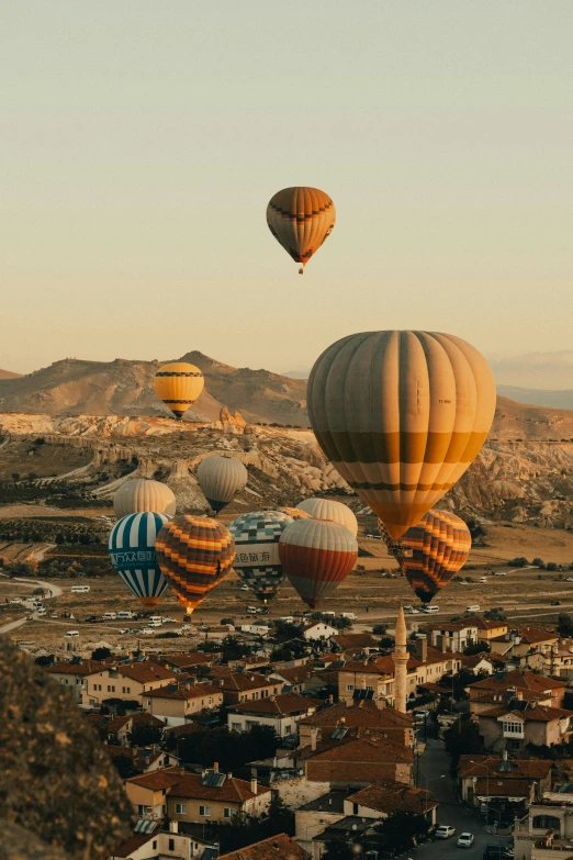 several balloons flying over the town in a valley