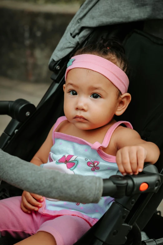 a small baby wearing pink and sitting in a stroller