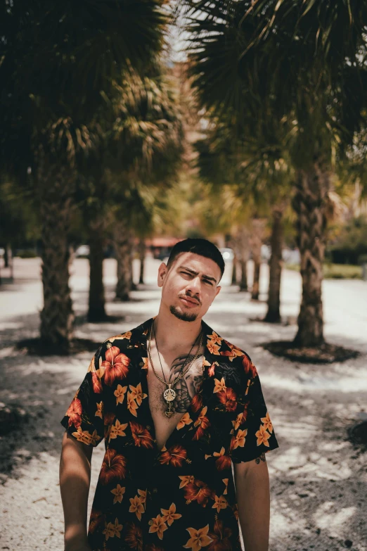 man with shirt on in middle of dirt road between palm trees