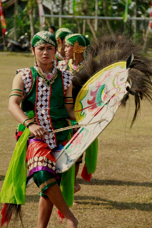 dancers in traditional dress walking with parasols at outdoor event