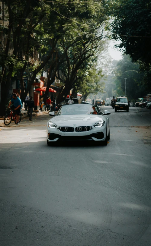 a white car is driving on a street in the daytime