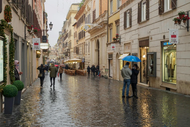 people walking on a wet street while holding an umbrella