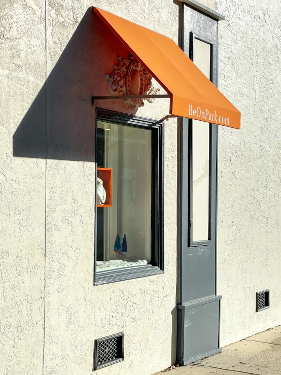 a tall orange awning in front of an open window