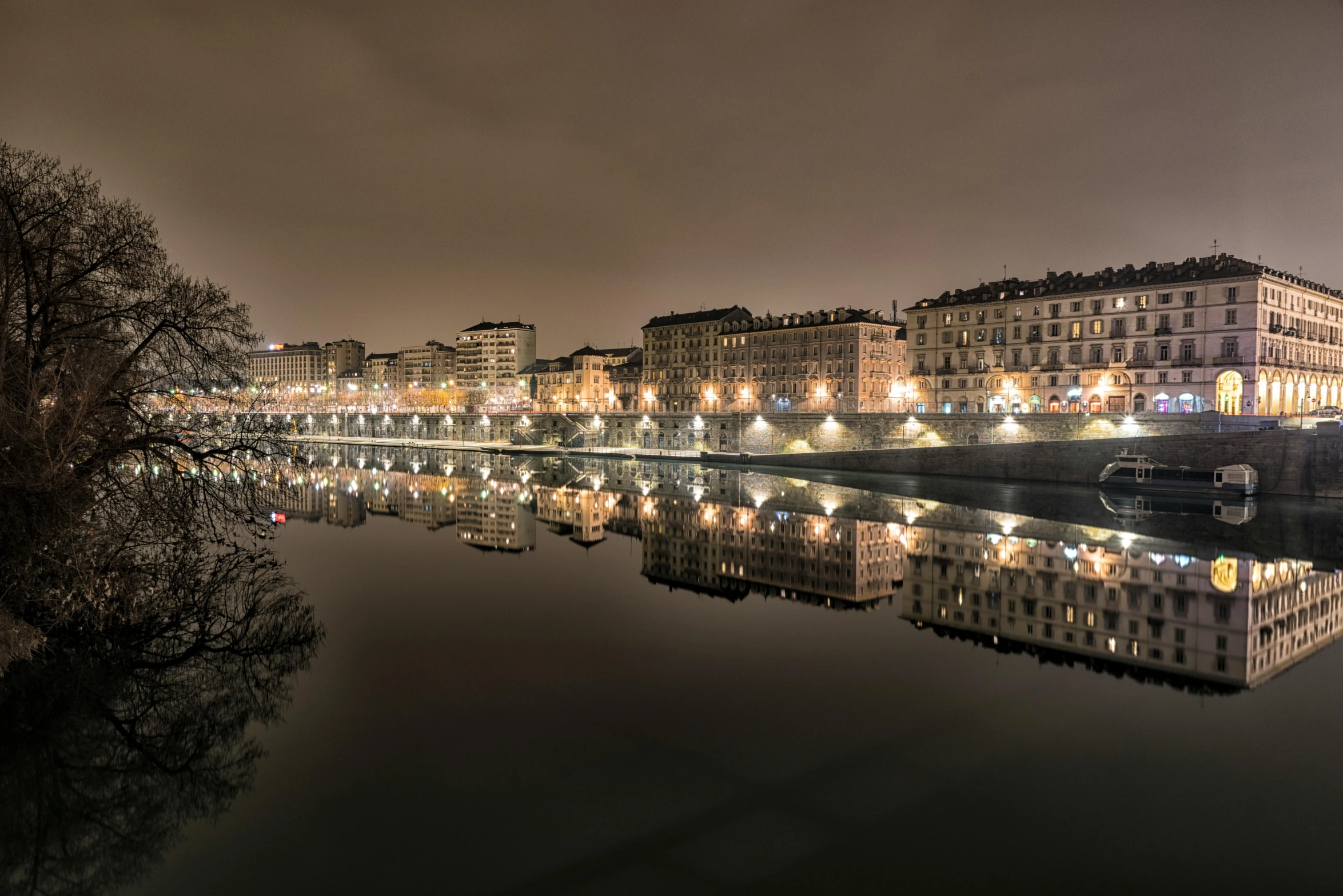 a city is seen at night and the water reflects