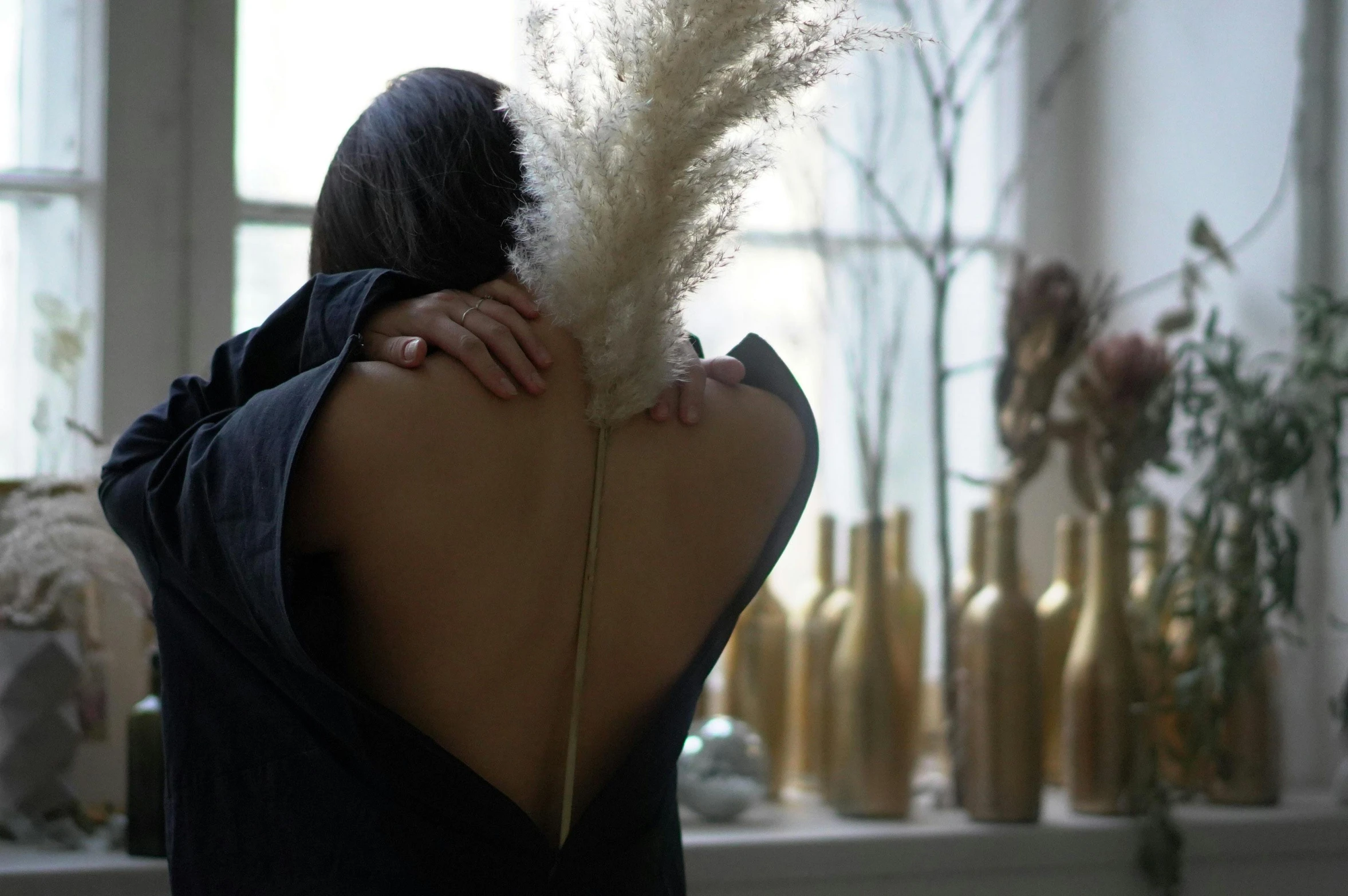 woman sitting with back to wall holding a plant