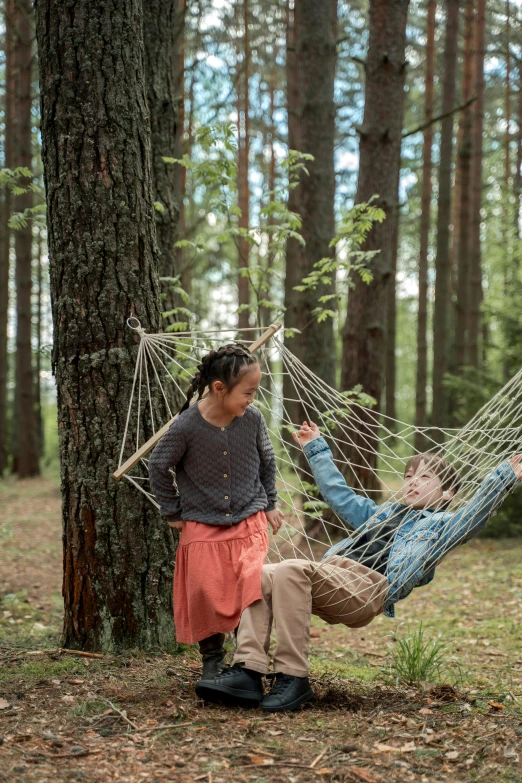 a woman standing on her knees next to a man laying in a hammock