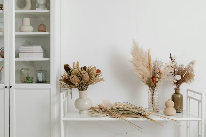 three vases on a shelf with dried flowers