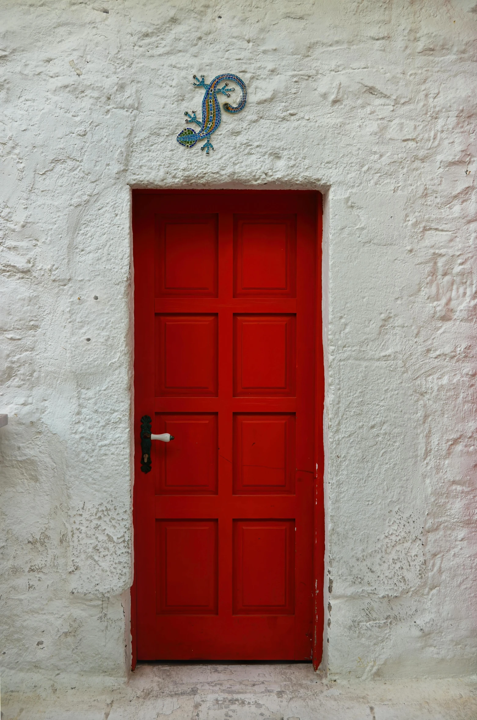 a large red door with an ornate wall decoration behind it